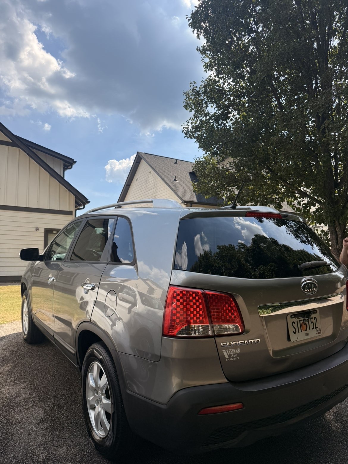 Rear and side of a silver Kia Sorento with reflective paint and clean tires.