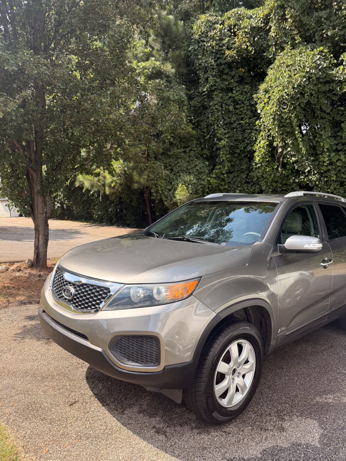 Front and side of a silver Kia Sorento after a detail, with clean wheels and shiny paint.
