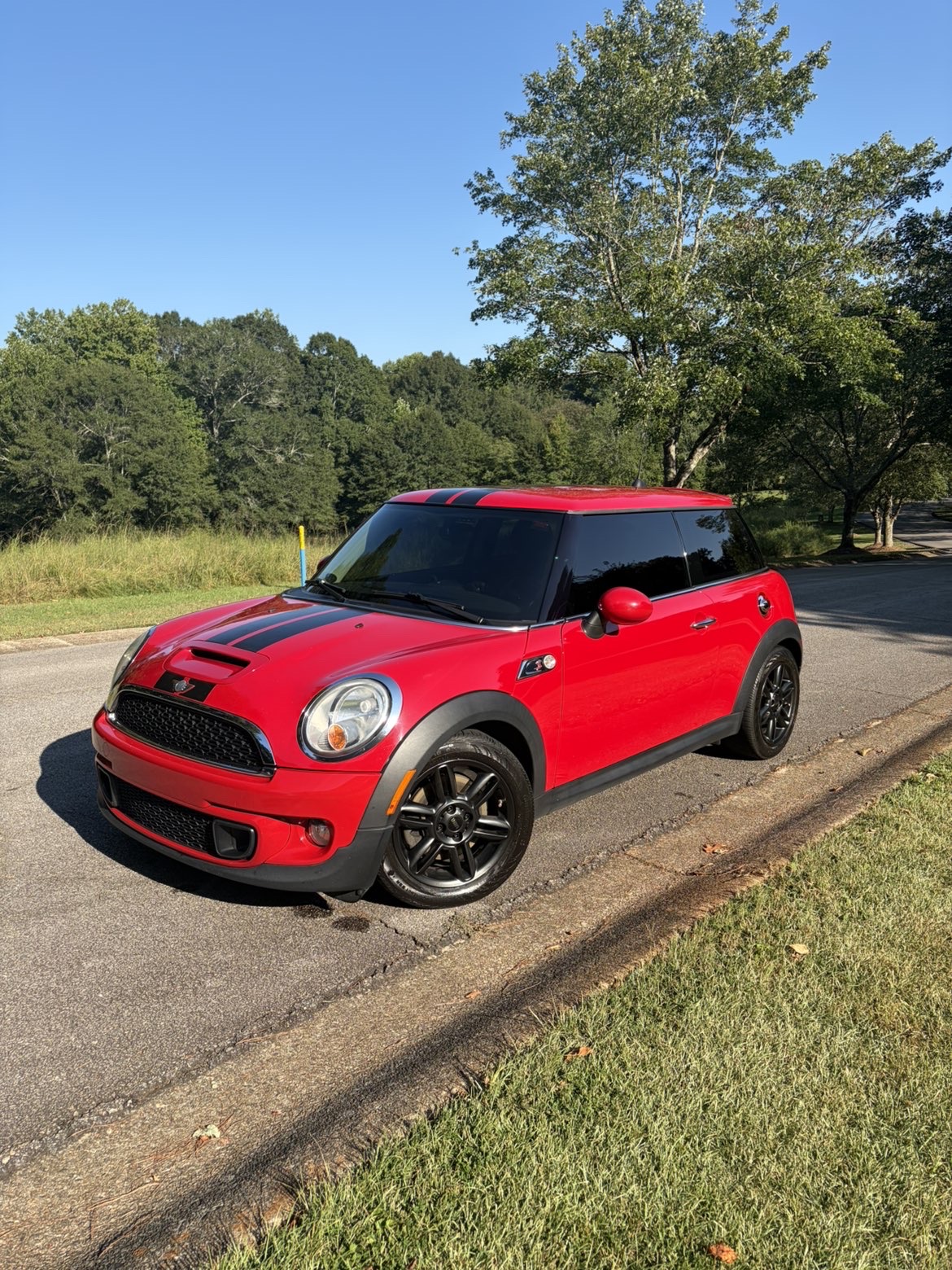 Red Mini Cooper with black hood stripes and clean black wheels, viewed from the front.