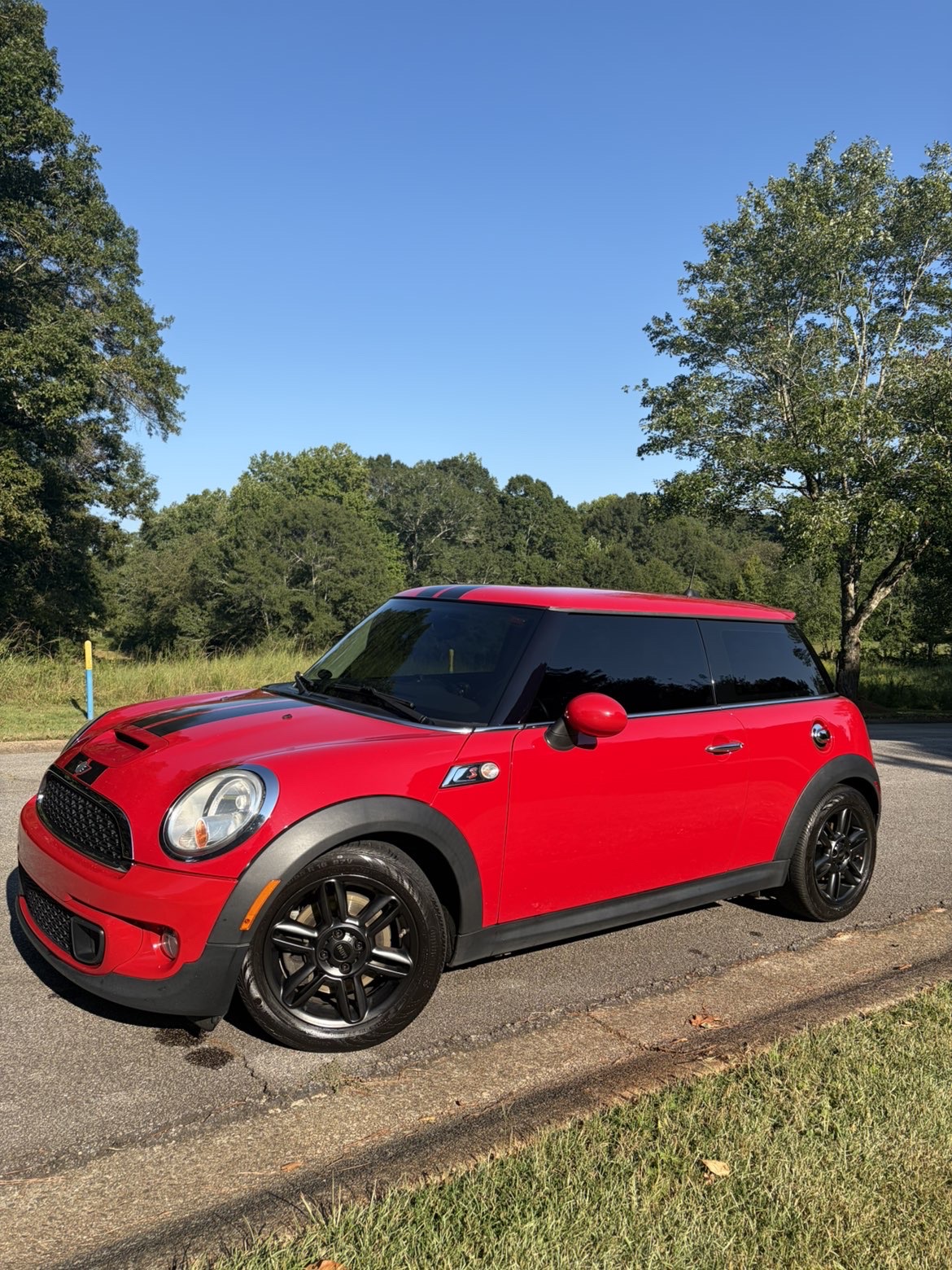 Freshly detailed red Mini Cooper with glossy black wheels, parked in the sunshine.