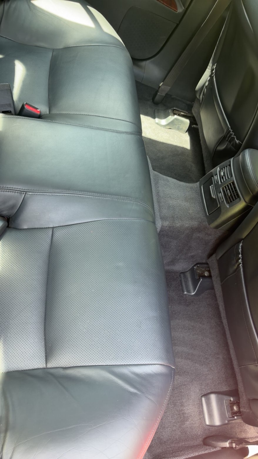 Clean black leather rear seats and vacuumed carpet in a car interior.