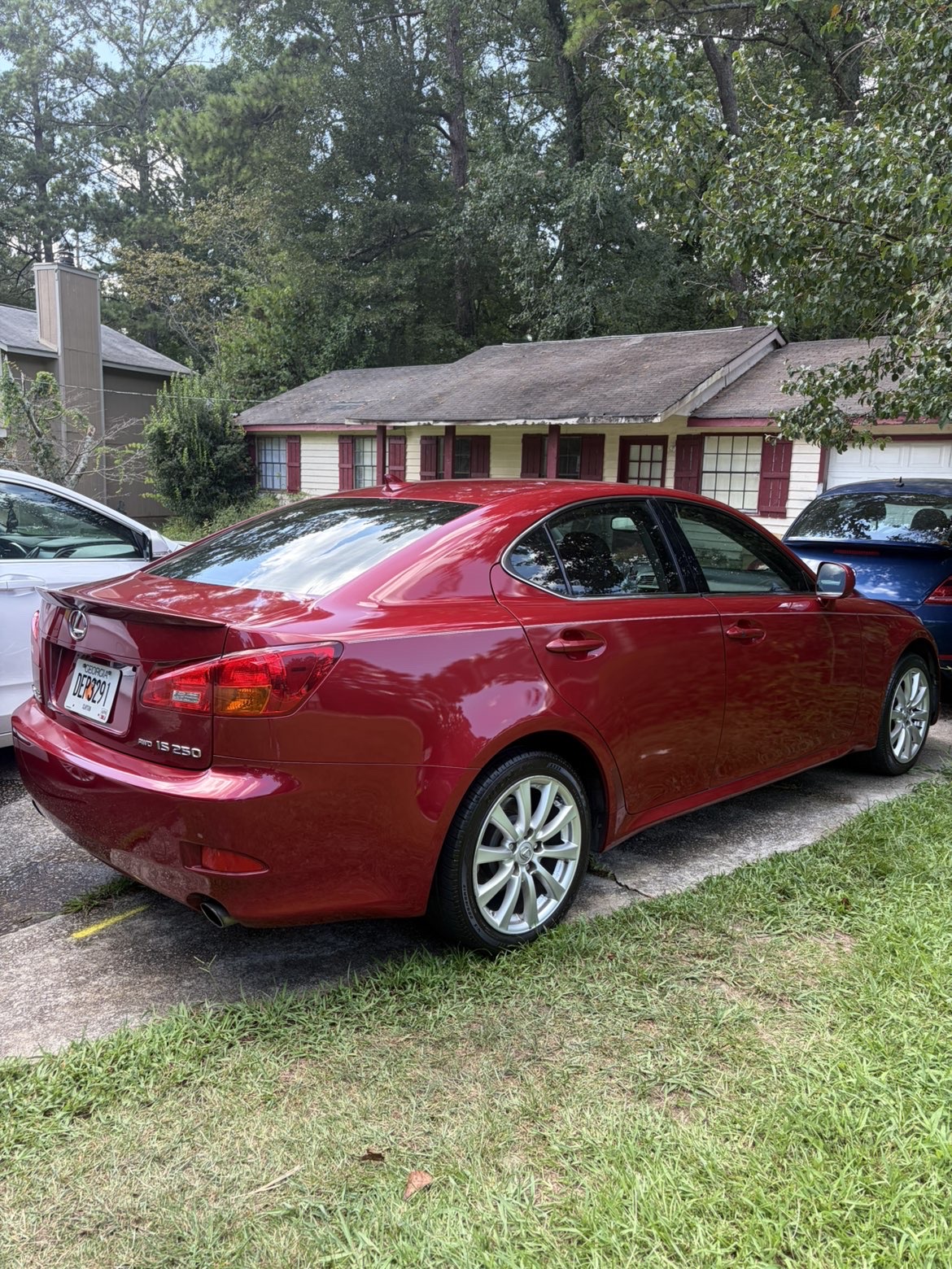 Red Lexus sedan with glossy paint and clean silver wheels, parked in a driveway.